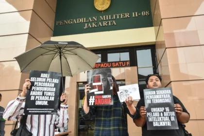 Aktivis KontraS membentangkan poster tuntutan usai Tim Advokasi untuk Demokrasi (TAUD) menyerahkan surat permintaan penghentian persidangan kasus dugaan penyiraman air keras terhadap aktivis KontraS Andrie Yunus di halaman Pengadilan Militer II-08 Jakarta, Senin (8/6/2026).
