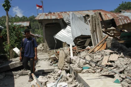 Warga melintas di samping bangunan rumah yang roboh akibat gempa bumi magnitudo 7,7 di Pulau Palue, Kabupaten Sikka, NTT, Rabu (19/8/2026).